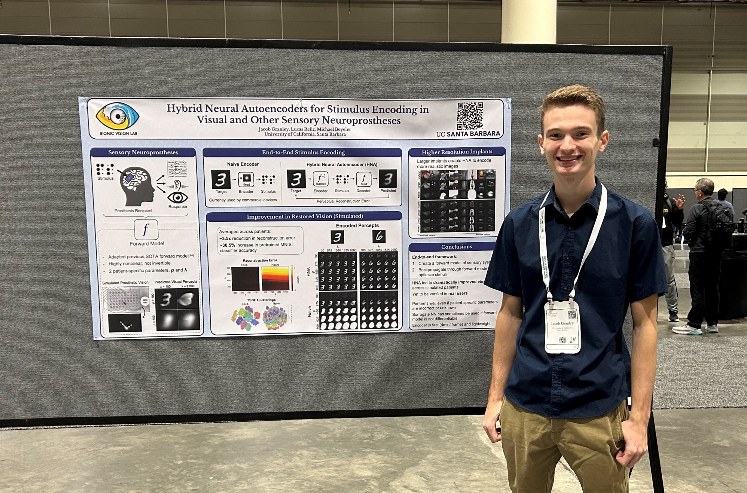 Jacob Granley smiles beside a poster titled “Hybrid Neural Autoencoders for Stimulus Encoding in Visual and Other Sensory Neuroprostheses” in the NeurIPS 2022 poster hall.